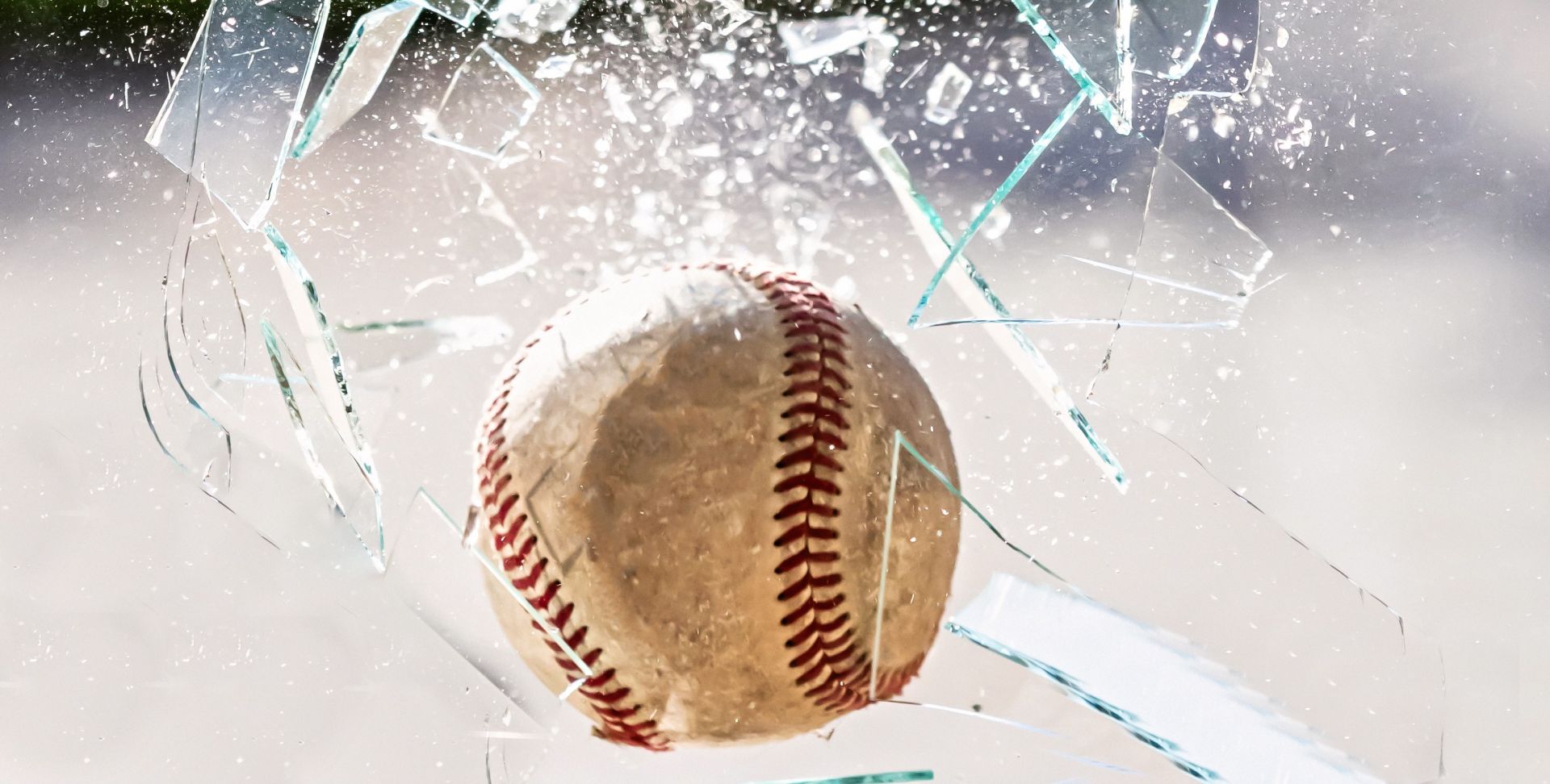 A baseball shattering a glass window